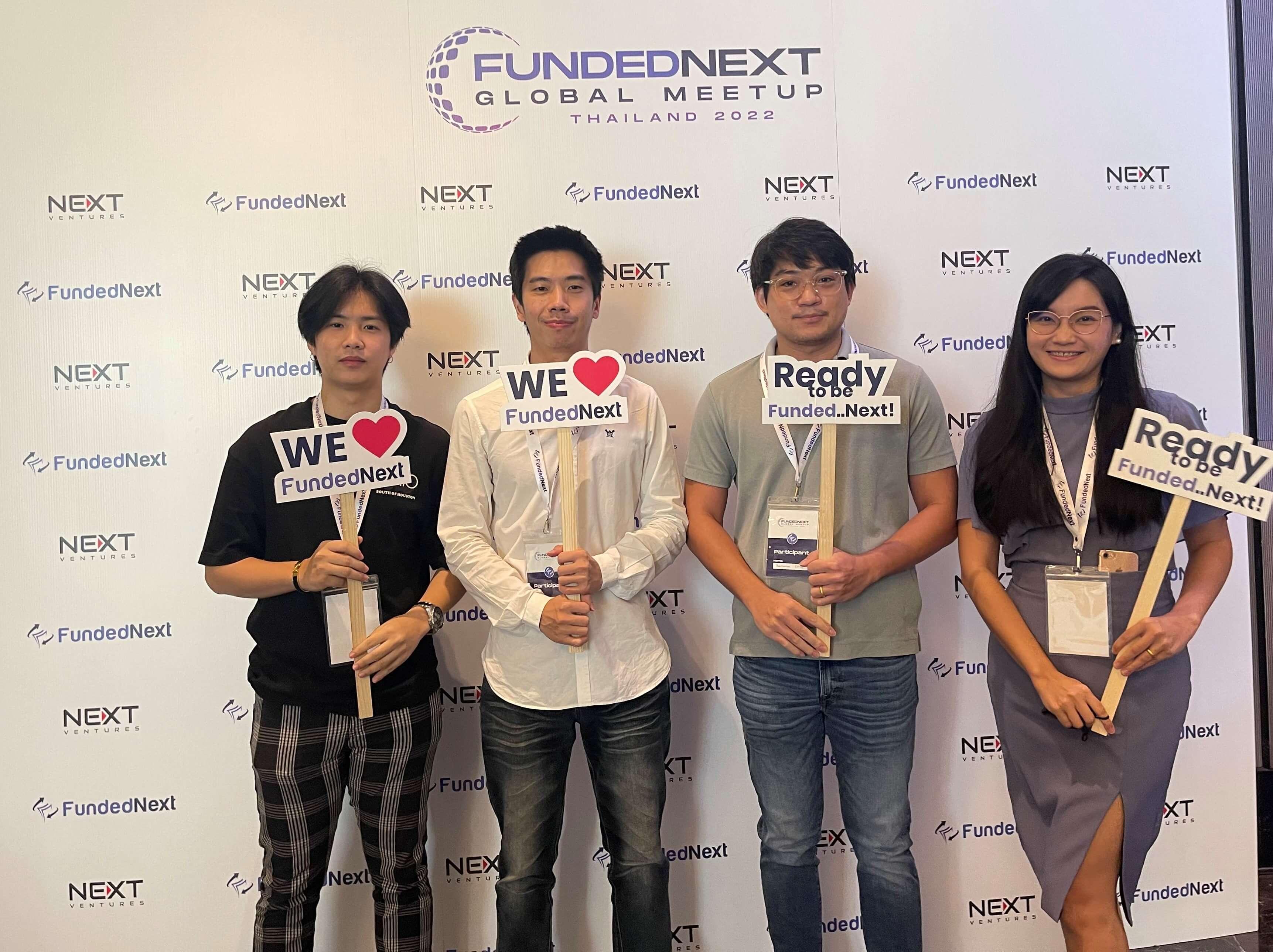 Four Traders at FundedNext Conference Holding Signs "I Love FundedNext"