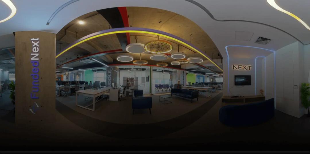 A wide-angle panoramic view of the modern FundedNext office, showing open-plan workstations and glass-walled meeting rooms.